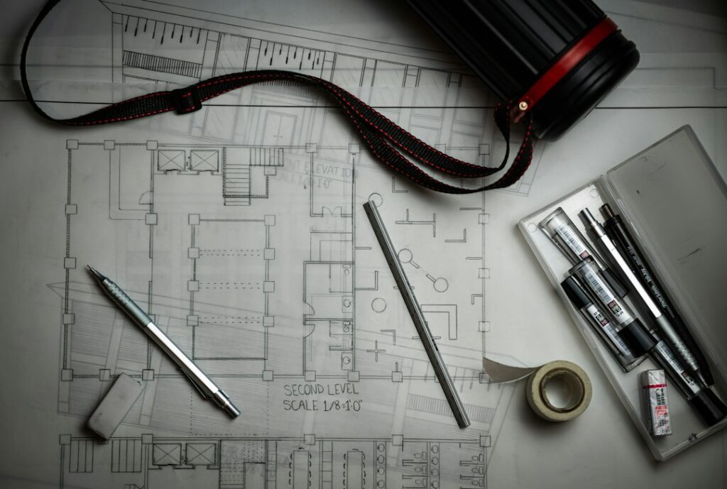 Architectural floor plans with drafting pencils, a ruler and a plan storage tube