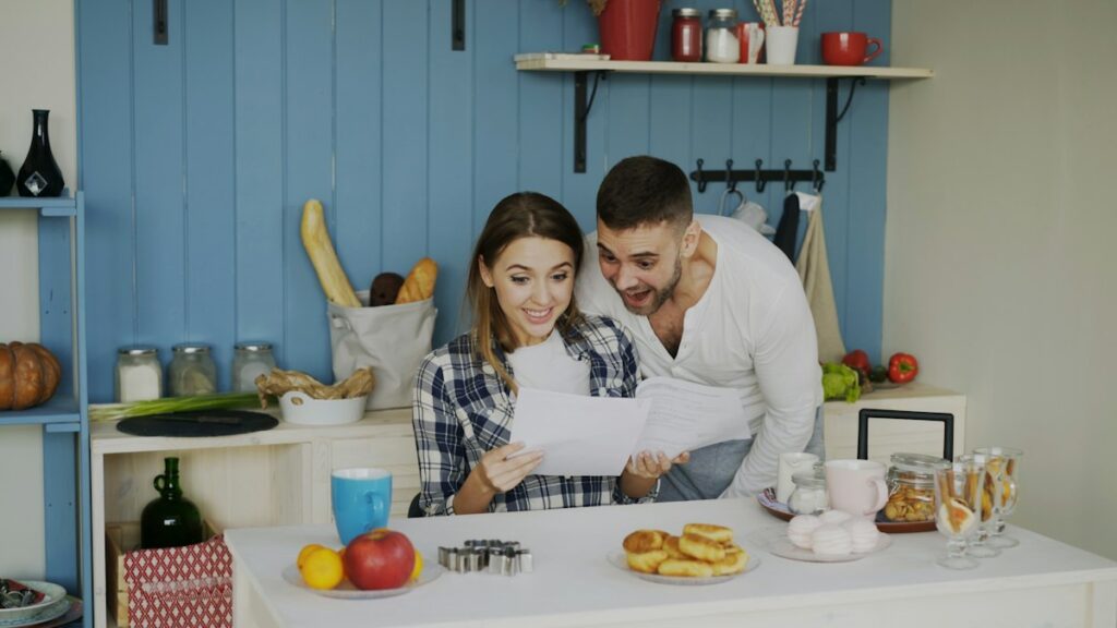 Couple reading a letter together at a kitchen counter