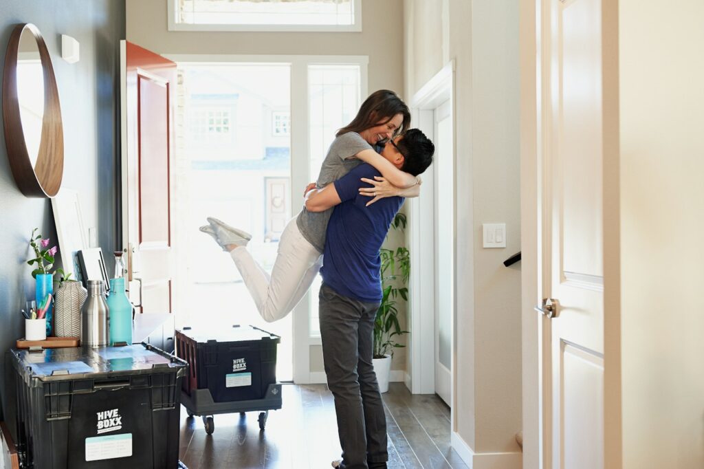 Couple embracing in a home entryway beside moving boxes