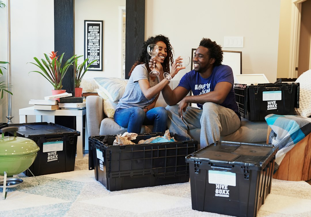 A couple celebrating on a sofa surrounded by moving boxes in their new home